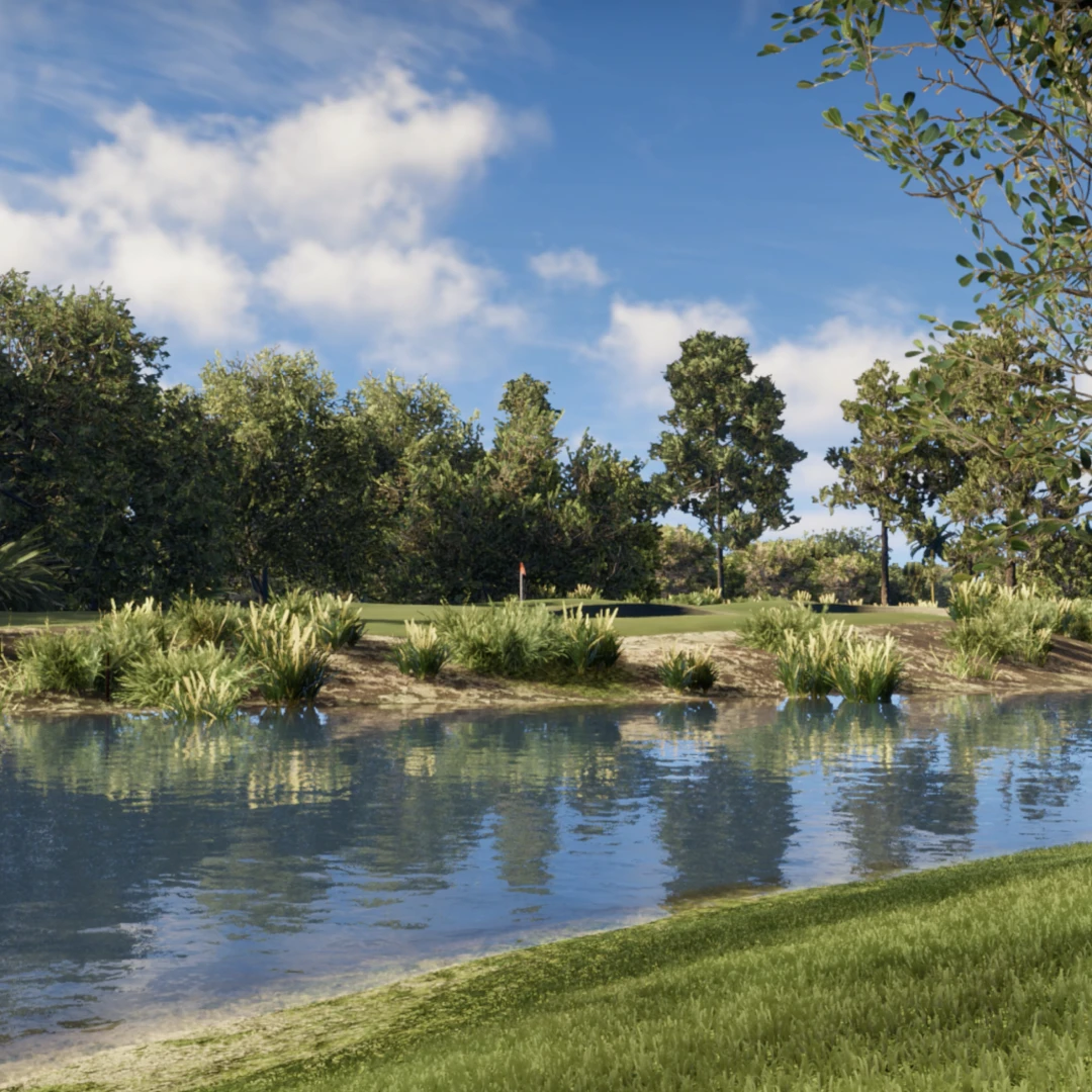 A serene view of a golf course with a pond in the foreground, lush grass, and tall trees under a partly cloudy blue sky.