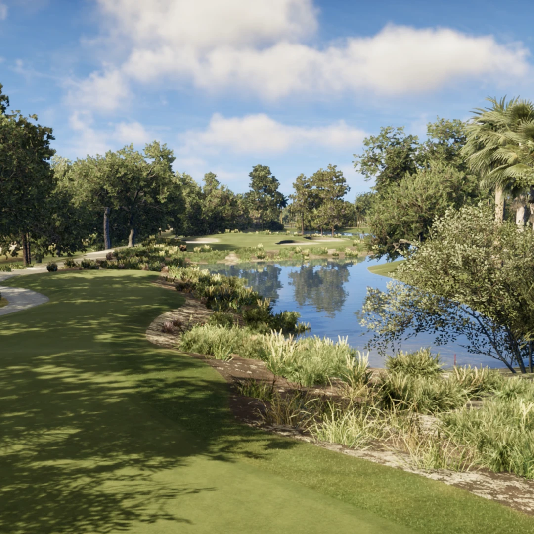 Scenic golf course with lush greenery, trees, a winding path, and a calm pond under blue skies with fluffy clouds.