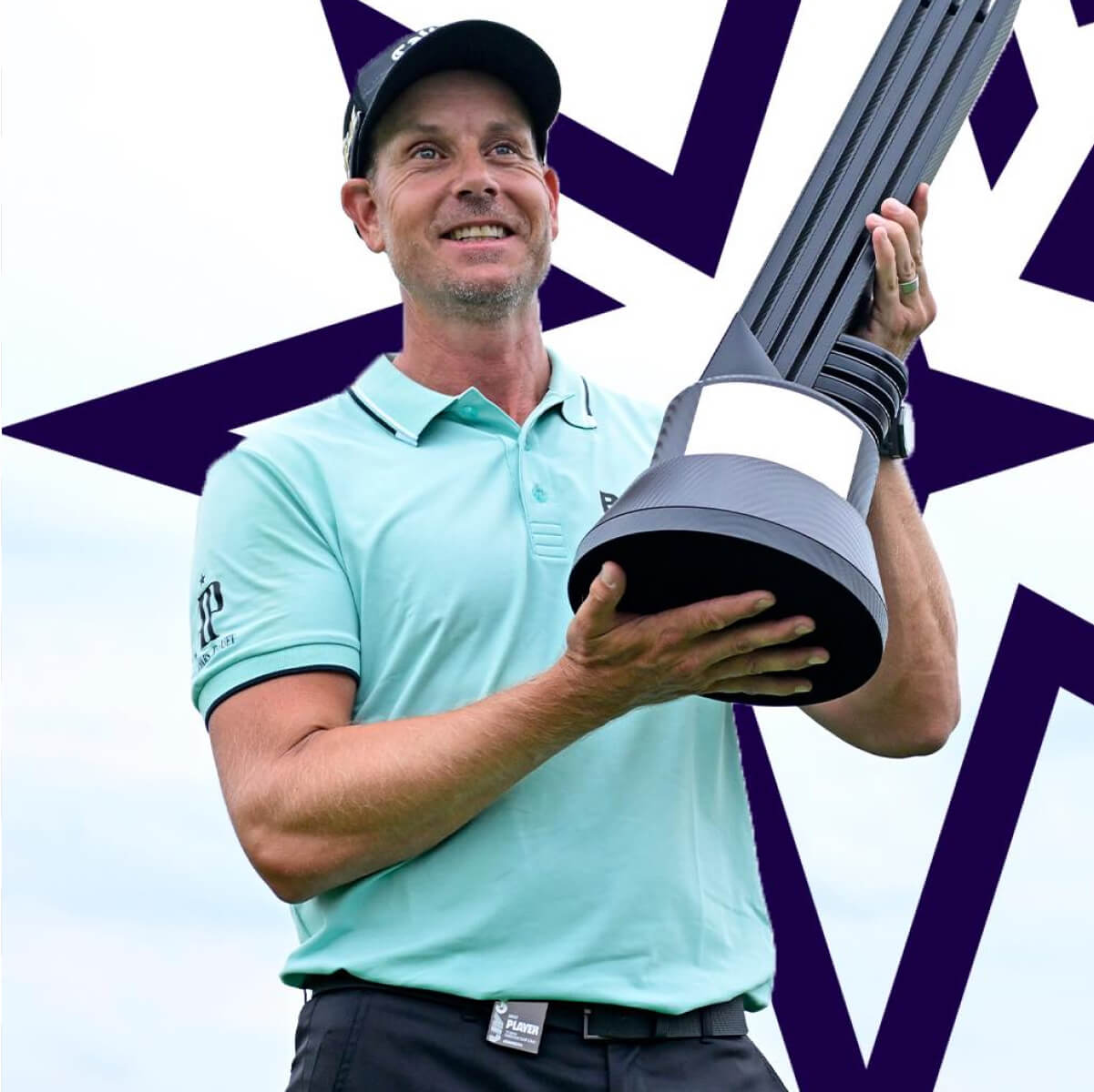 Golfer Henrik Stenson in a light blue shirt holds a large trophy with a star pattern in the background.