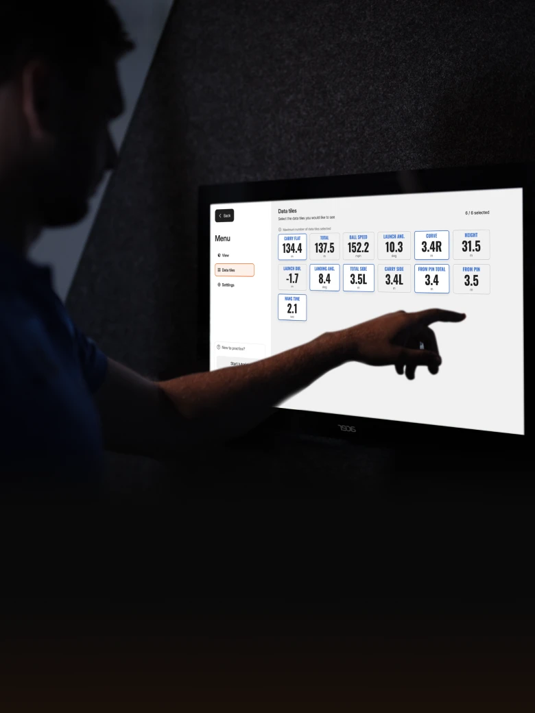 Silhouette of a person pointing at a screen displaying data metrics in a dimly lit room.