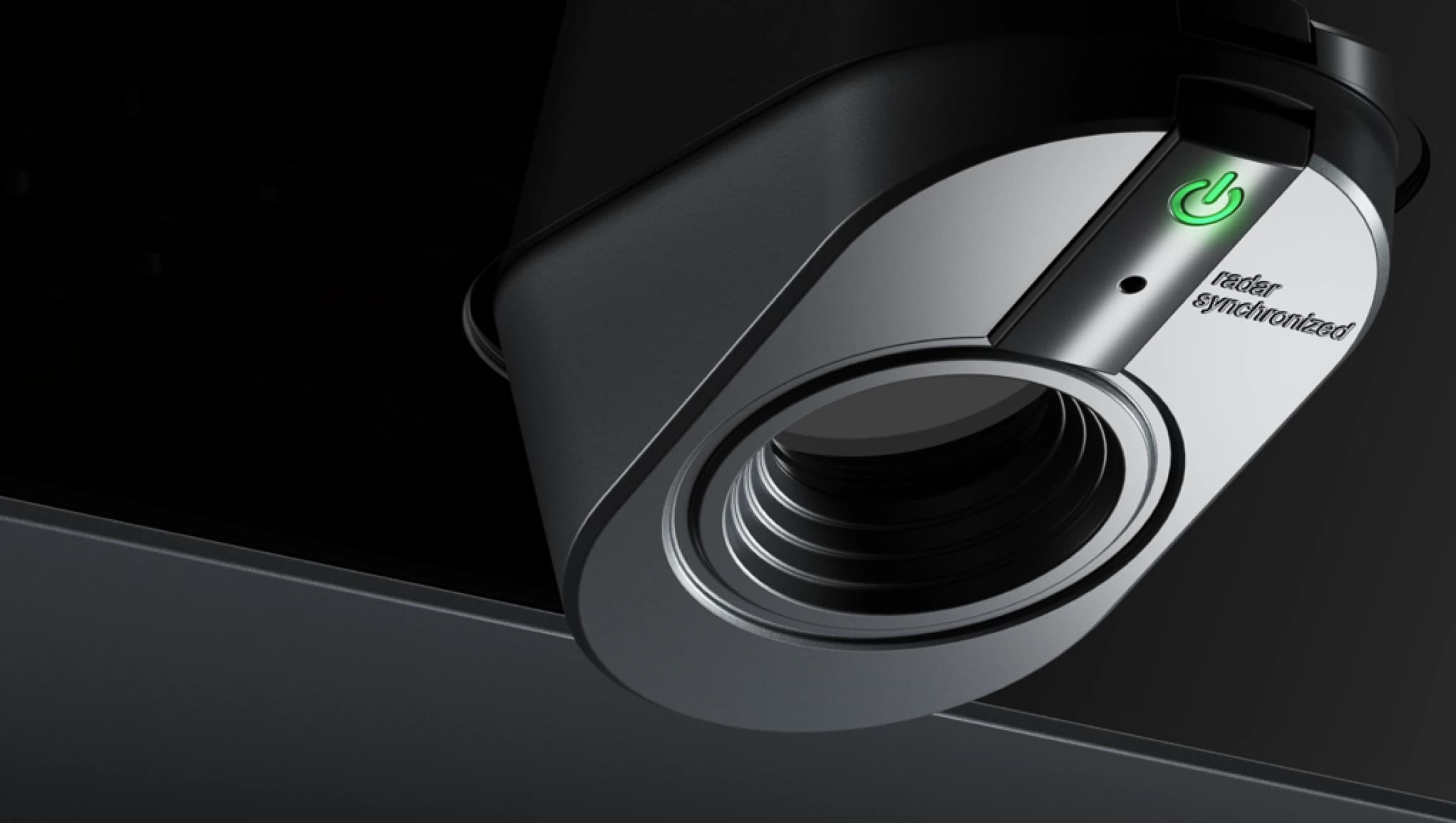 Close-up of a sleek, black device with a circular opening and a green power button labeled "radar synchronized."